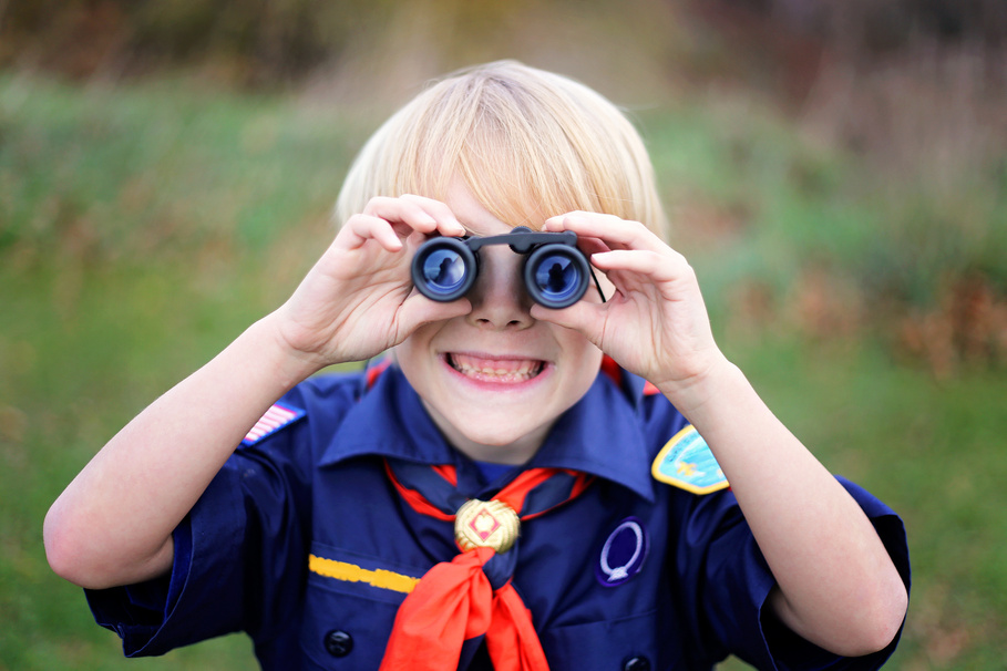 Young Tiger Cub Scout Smiling at Camera Through Binoculars